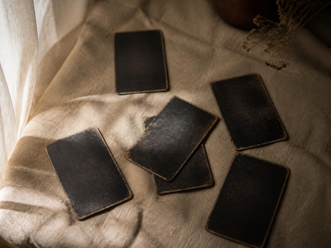 Cartas de tarot boca abajo sobre lino color arena con luz de ventana
